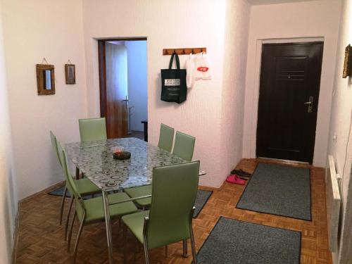 a dining room with a table and green chairs at Niš Apartman in Niš