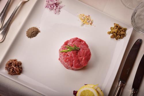 a piece of meat on a white plate with spices at Hotel Valtellina in Livigno