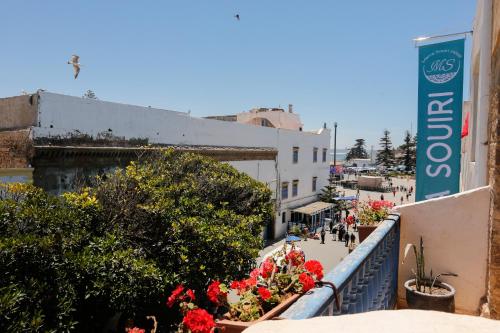 a balcony with flowers and a sign on a building at Mama Souiri Hotel in Essaouira