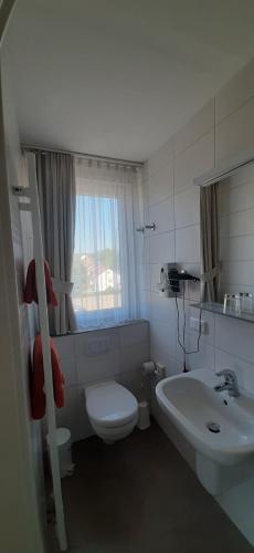 a white bathroom with a toilet and a sink at Landgasthof Zur scharfen Ecke in Hildesheim