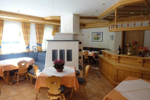 a restaurant with tables and chairs and a staircase at Pension Alpenrose in Maishofen