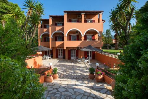 a large orange building with palm trees in front of it at Villa Pami in Almiros Beach