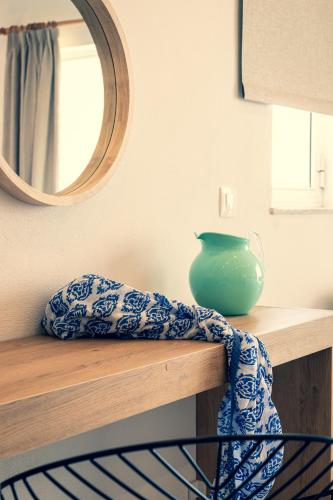 a green vase sitting on a wooden shelf with a mirror at Euphoria Blue studio apartments in Artemida