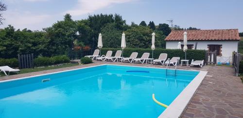 a blue swimming pool with chairs and a house at Agriturismo La Guinza in Arcidosso