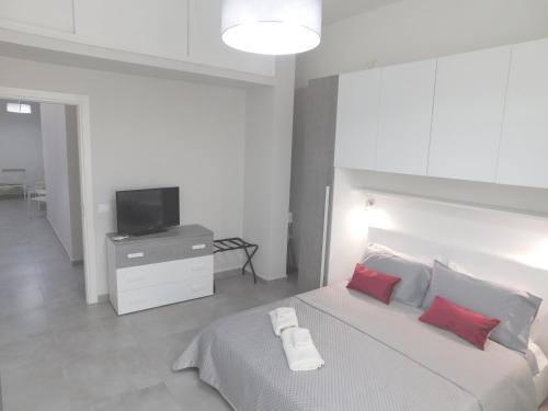 Schlafzimmer mit einem Bett mit roten Kissen und einem TV in der Unterkunft Palermo Relax in Palermo