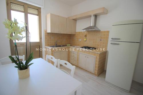 a kitchen with a white table and a refrigerator at Home Holiday Salento Monica's House Pescoluse in Marina di Pescoluse