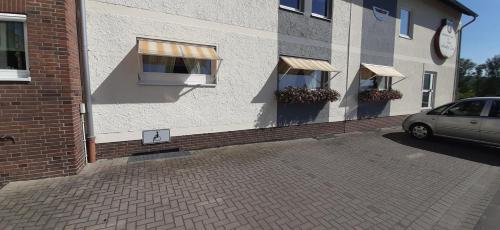 a building with two windows and a car parked outside at Landgasthof Zur scharfen Ecke in Hildesheim