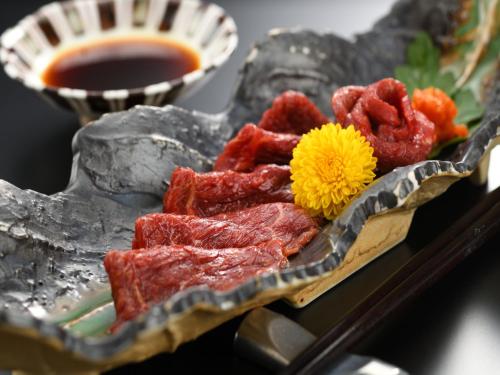 a plate of food with meat and a yellow flower at Eirakukan in Koriyama