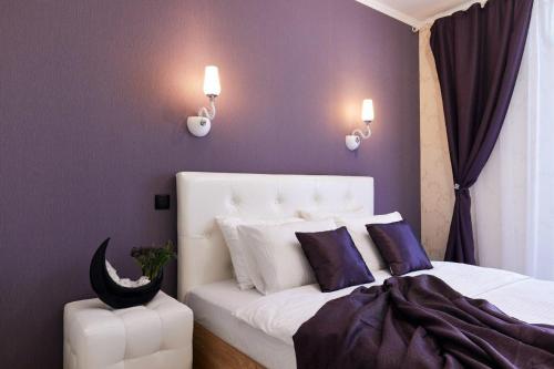 Un dormitorio con una cama blanca con paredes moradas en PaulMarie Apartments on Mayakovskogo, en Minsk
