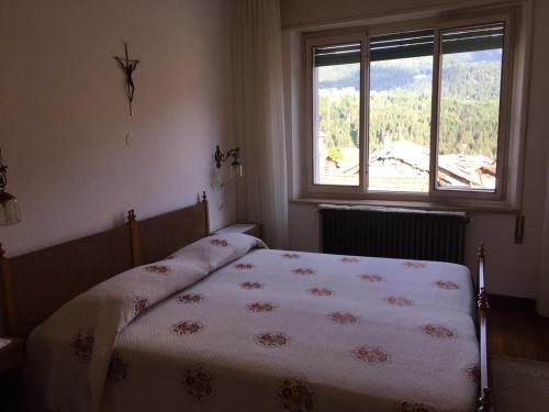 Schlafzimmer mit einem Bett und einem Fenster in der Unterkunft Casa Giuditta in Lozzo Cadore