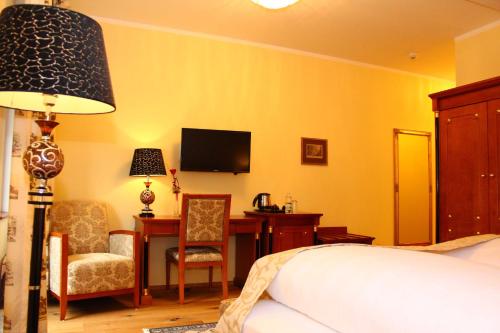 a bedroom with a bed and a desk and a television at Seehotel Grüner Baum in Hallstatt