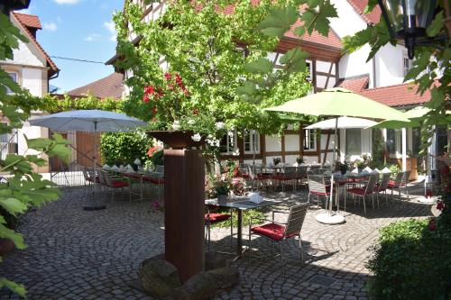 a courtyard with tables and chairs and a tree at Landhotel Hauer in Pleisweiler-Oberhofen