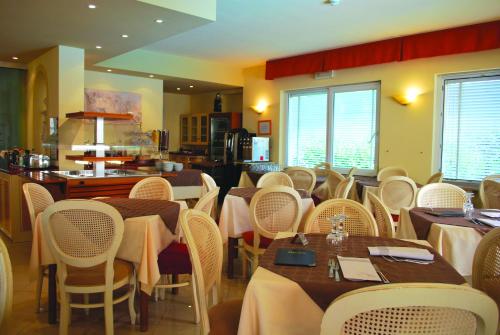 a restaurant with tables and chairs and a kitchen at Hotel Alsazia in Sirmione