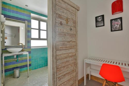 baño con puerta de madera y silla roja en Mama Souiri Hotel, en Essaouira