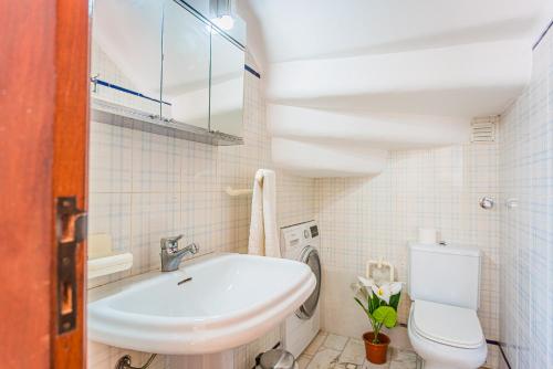 a white bathroom with a sink and a toilet at Estrela de Sesimbra in Sesimbra