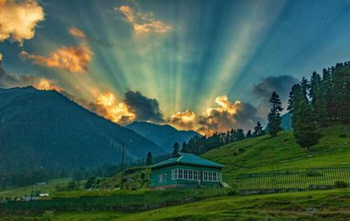 a rainbow in the sky over a house in a field at S Group Of Houseboat in Srinagar