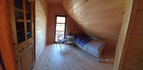 a bedroom in a log cabin with a bed and a window at Sowia chatka in Bożkowice