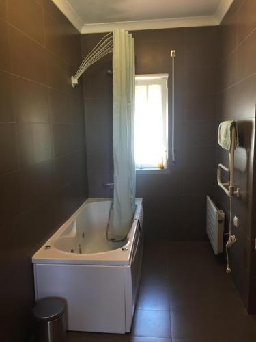 a bathroom with a bath tub with a window at Holiday home Monte das Azinheiras in Arraiolos