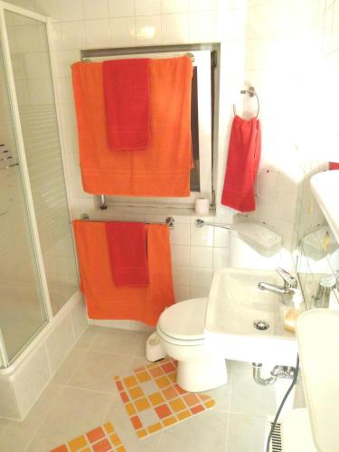 a bathroom with orange towels and a toilet and a sink at Harzhaus Willkommen in Braunlage
