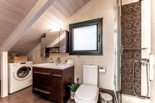 a bathroom with a toilet and a sink and a washing machine at Gregory’s Loft in Ayia anna