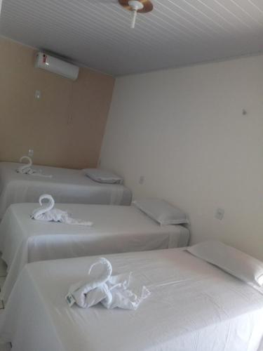 three beds in a room with white sheets at Pousada Bela Vista de Mateiros in Mateiros