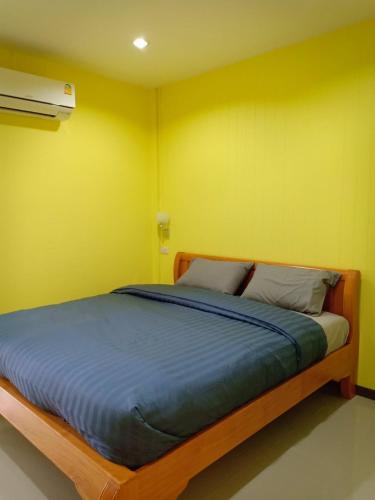 a bed in a room with a yellow wall at Siri Guesthouse in Phra Nakhon Si Ayutthaya