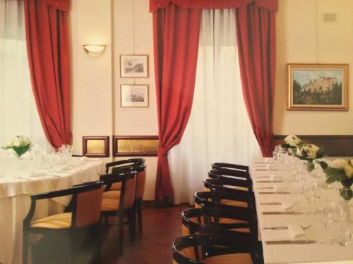 a dining room with white tables and chairs and red curtains at Albergo Sacro Monte Varese in Varese