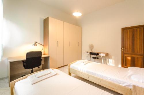Zimmer mit 2 Betten, einem Schreibtisch und einem Stuhl in der Unterkunft Emil's House, Spazioso appartamento con 3 camere in Bologna