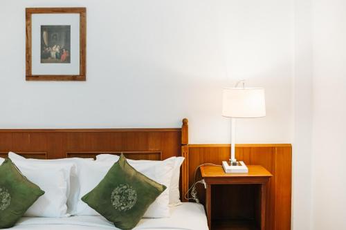 a bedroom with a bed with a lamp on a table at Rendezvous Oldtown Chiangmai in Chiang Mai