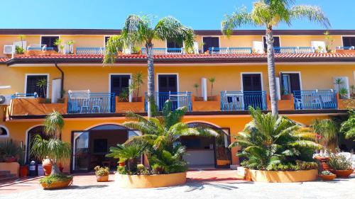 an orange building with palm trees in front of it at Hotel Grotticelle in Capo Vaticano