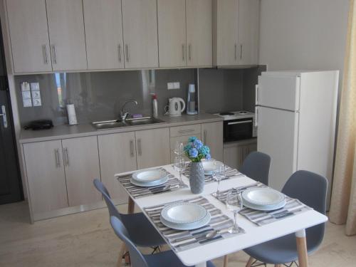 a kitchen with a table with chairs and a white refrigerator at Blue Yard Apartments in Kalamata