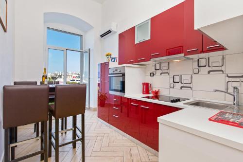 cocina con armarios rojos y ventana grande en Apartment Mia, en Rijeka