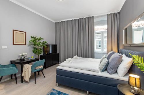 a bedroom with a blue bed and a table and chairs at Apartments Carpathia in Rijeka