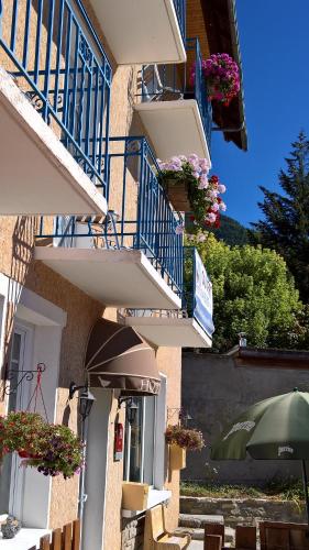 a building with balconies with flowers and a green umbrella at Les Fauvettes in Saint-Léger-les-Mélèzes