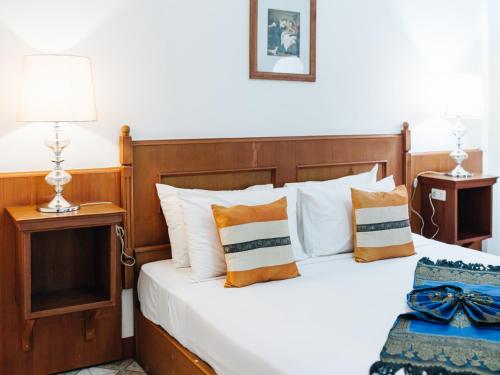 a bedroom with a bed with white and orange pillows at Rendezvous Oldtown Chiangmai in Chiang Mai