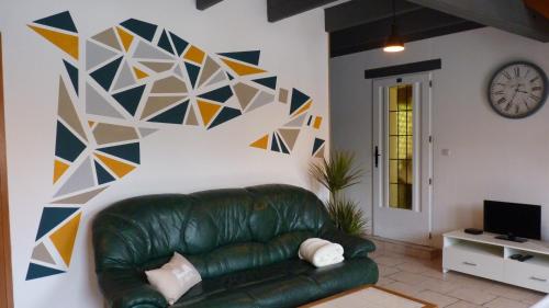 uma sala de estar com um sofá de couro verde e um relógio em Gite la Ville Brunet em Saint-Briac-sur-Mer