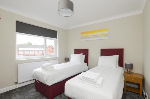 two beds in a room with a window at Cosy House in the heart of Beeston with FREE Parking and WiFi in Nottingham