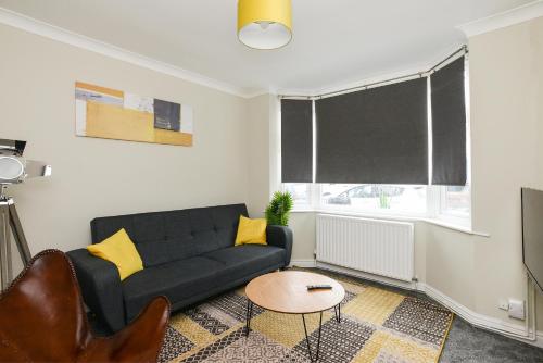 a living room with a black couch and a window at Cosy House in the heart of Beeston with FREE Parking and WiFi in Nottingham