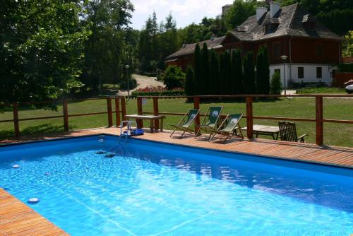 a swimming pool with two chairs and a table at Dworek Karpińskich in Sandomierz