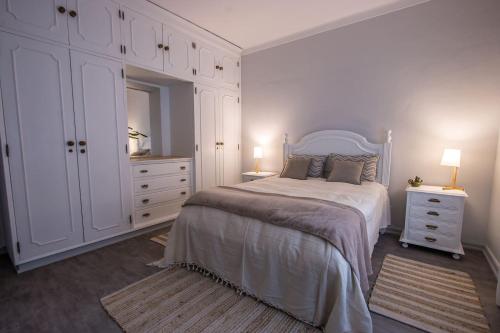 a white bedroom with a bed and white cabinets at Carvalhos House in Sintra