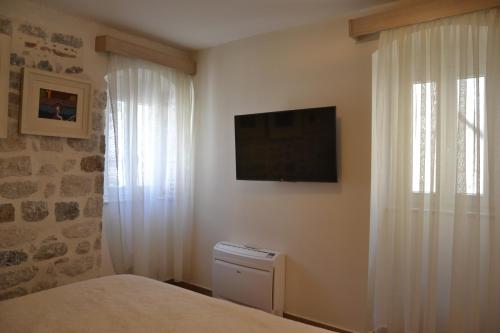a bedroom with a bed and a television on the wall at Apartmani Art Karampana in Kotor