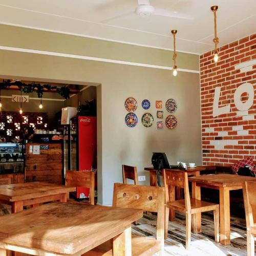 a restaurant with wooden tables and chairs and a brick wall at Mahali Guesthouse, Makindye Hill in Kampala
