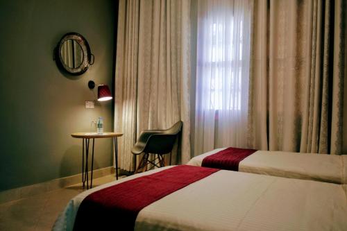 a hotel room with two beds and a table and a window at Mahali Guesthouse, Makindye Hill in Kampala