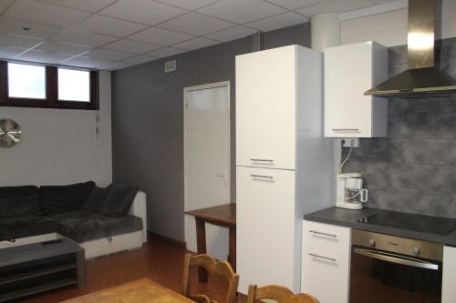 Il comprend une cuisine et un salon avec des placards blancs et un canapé. dans l'établissement Hotel du Lac - Au Bord du Lac, à La Tour-dʼAuvergne