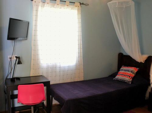 1 dormitorio con cama, escritorio y ventana en Casa Rural Los Membrillos, en Teba
