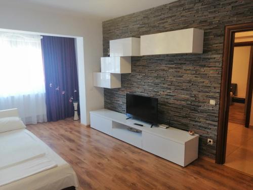 1 dormitorio con TV en una pared de ladrillo en Apartament Yfu Mamaia Nord, en Mamaia Nord – Năvodari