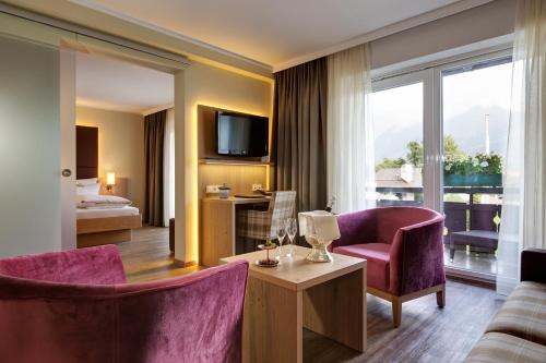 a hotel room with purple chairs and a living room at Obermühle 4*S Boutique Resort in Garmisch-Partenkirchen