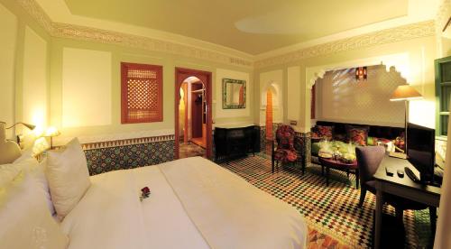 a bedroom with a large bed and a living room at Palais Faraj Suites & Spa in Fès
