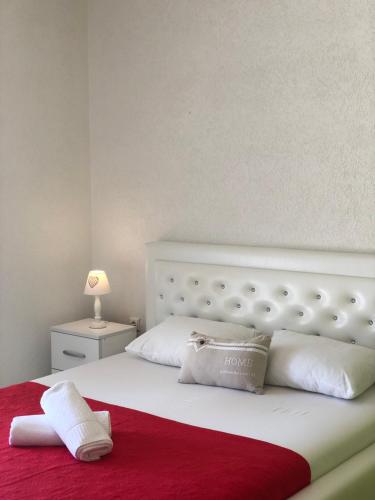 a white bed with a red blanket and white pillows at Apartmani Dini in Ulcinj