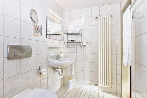 a white bathroom with a sink and a toilet at Ringhotel Haus Oberwinter in Remagen
